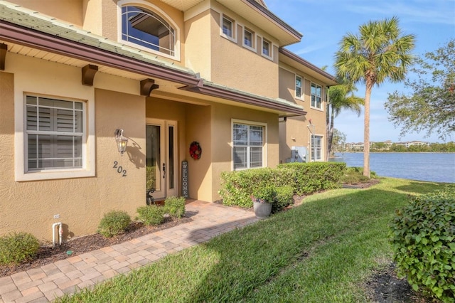 entrance to property featuring a lawn and a water view