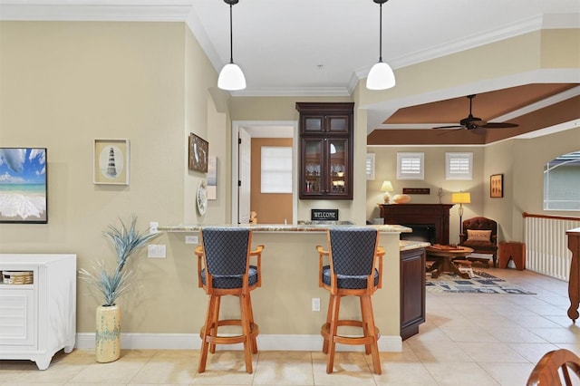 kitchen featuring dark brown cabinetry, a breakfast bar, crown molding, decorative light fixtures, and kitchen peninsula