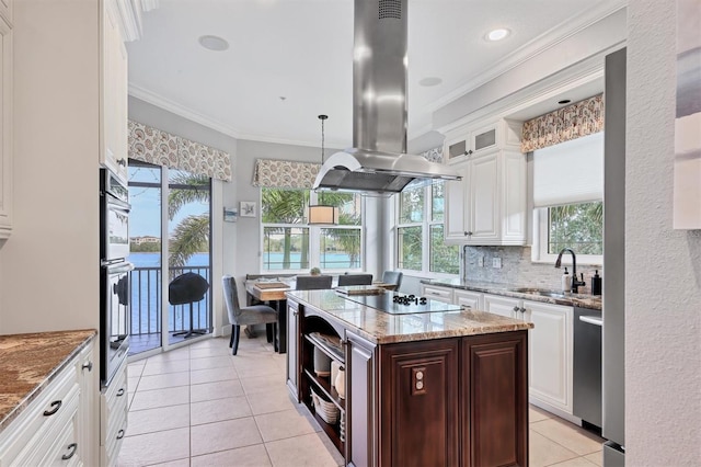 kitchen featuring island exhaust hood, a center island, light tile patterned floors, stainless steel appliances, and crown molding