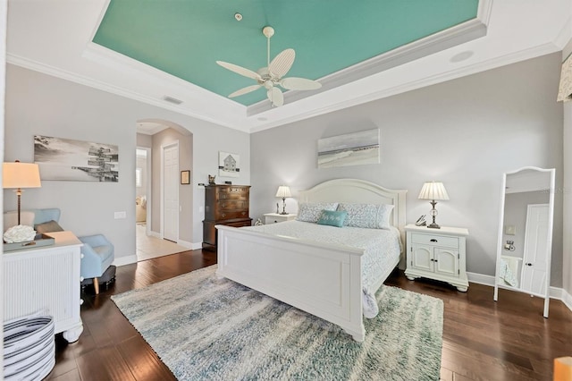 bedroom with ceiling fan, ornamental molding, dark hardwood / wood-style flooring, and a raised ceiling