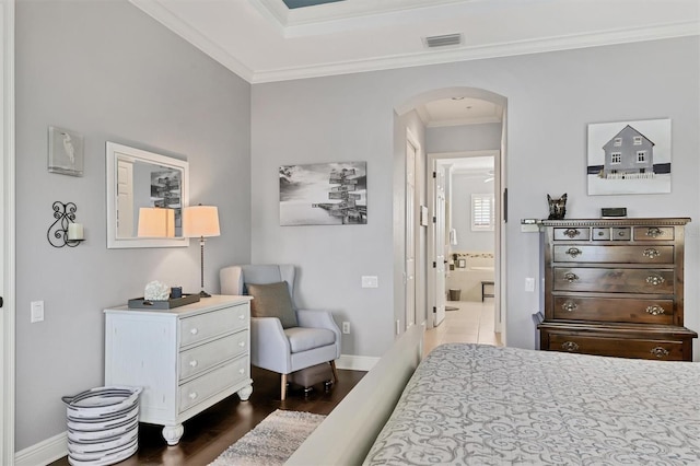 bedroom with ornamental molding, connected bathroom, and dark hardwood / wood-style flooring