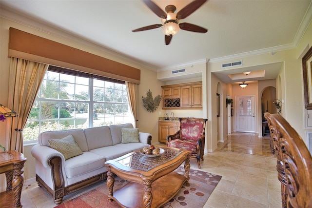 living room with ceiling fan, wet bar, and crown molding