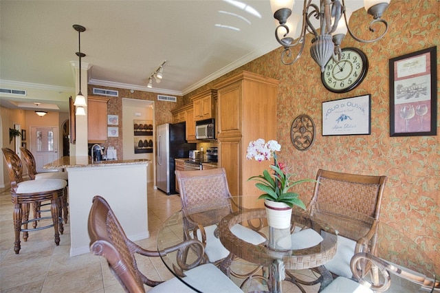 dining area featuring rail lighting, crown molding, sink, light tile patterned floors, and a chandelier