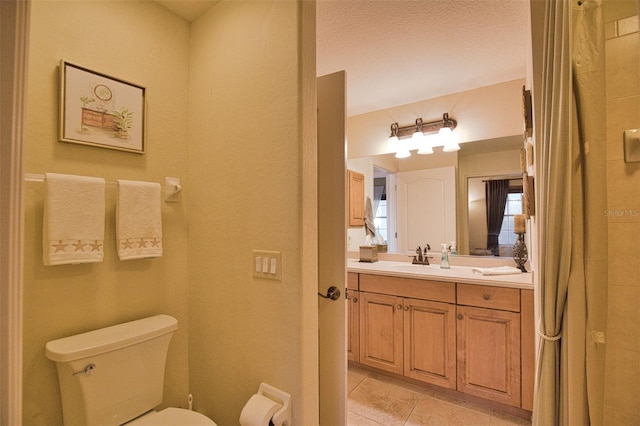 bathroom with tile patterned flooring, vanity, a textured ceiling, and toilet