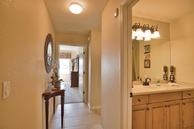 corridor featuring a textured ceiling, light tile patterned flooring, and sink