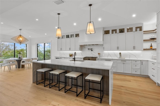 kitchen featuring white cabinetry, sink, a kitchen breakfast bar, an island with sink, and light hardwood / wood-style floors