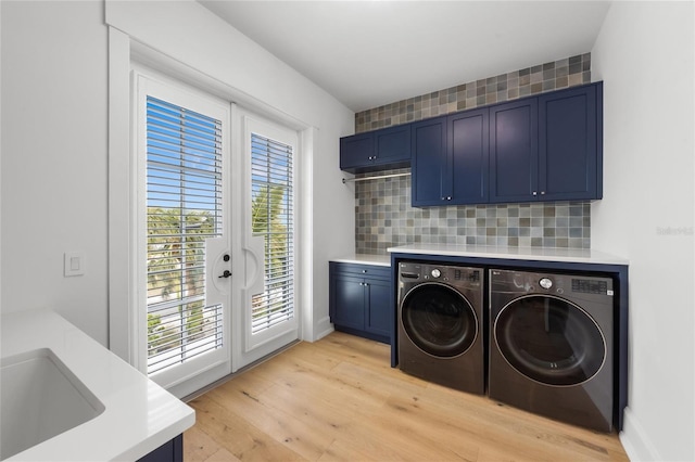 laundry area with cabinets, light hardwood / wood-style floors, a healthy amount of sunlight, and washing machine and clothes dryer