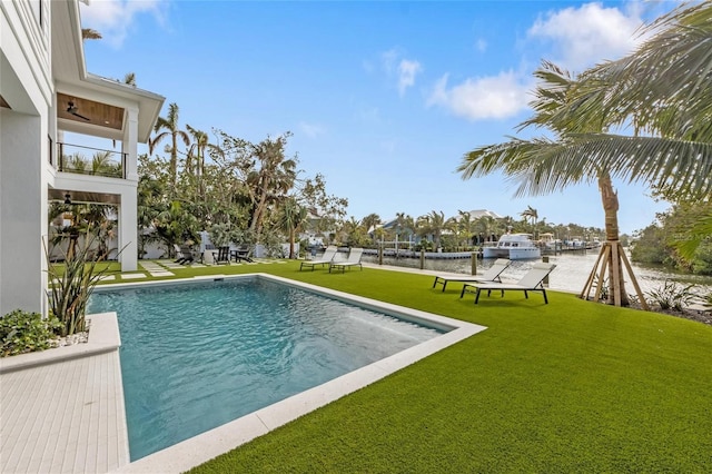 view of pool with a yard and a water view