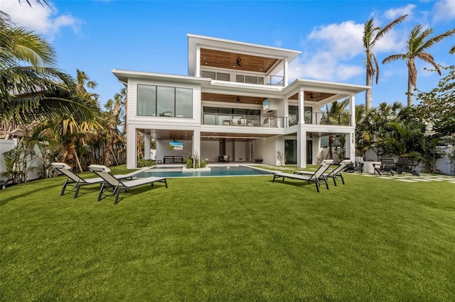 rear view of property featuring a yard, a balcony, a patio, and ceiling fan