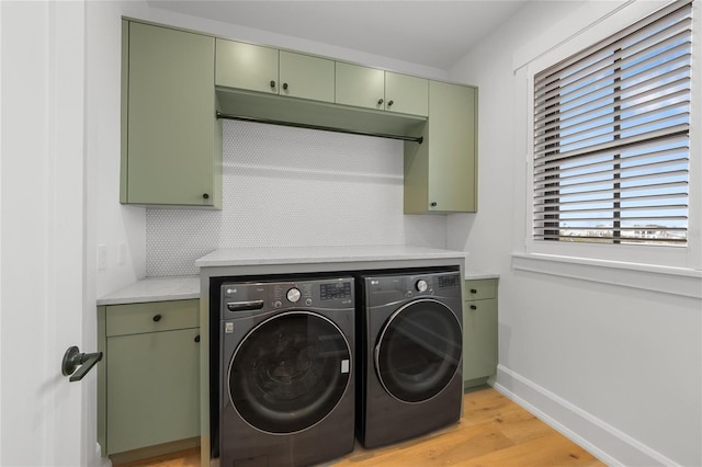 laundry area with washing machine and dryer, light hardwood / wood-style flooring, and cabinets