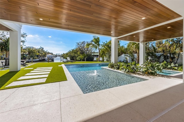 view of pool with a patio area, pool water feature, and a yard