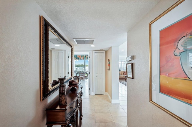 corridor featuring light tile patterned floors and a textured ceiling