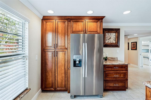 kitchen featuring stainless steel fridge, light tile patterned floors, light stone counters, and ornamental molding