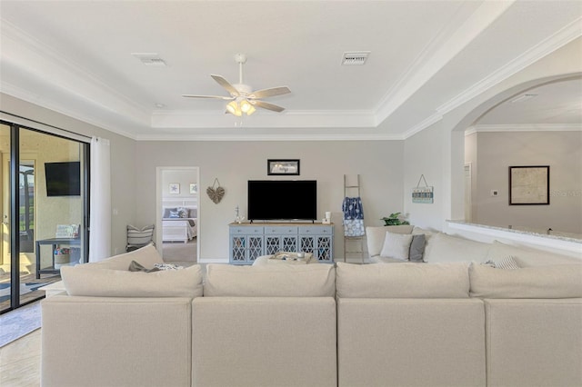 living room with ornamental molding, a raised ceiling, and ceiling fan