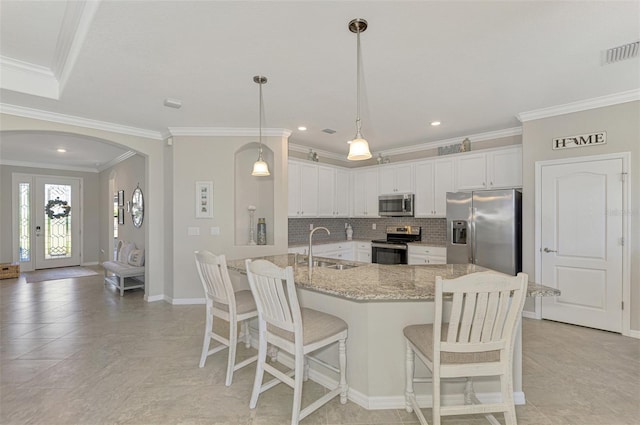 kitchen with appliances with stainless steel finishes, pendant lighting, white cabinets, and sink