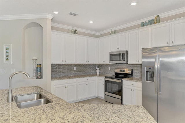 kitchen featuring sink, white cabinetry, light stone counters, appliances with stainless steel finishes, and decorative backsplash