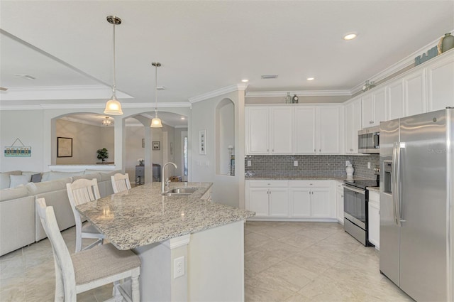 kitchen with a kitchen bar, stainless steel appliances, pendant lighting, white cabinets, and sink