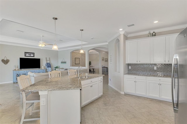 kitchen with white cabinets, sink, an island with sink, and light stone counters