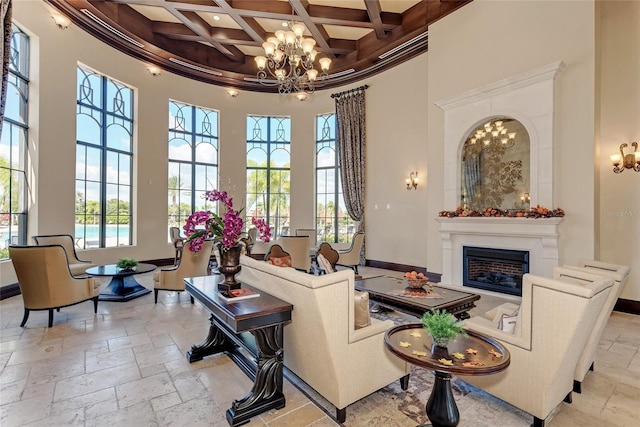 living room featuring a notable chandelier, beamed ceiling, a high ceiling, coffered ceiling, and ornamental molding