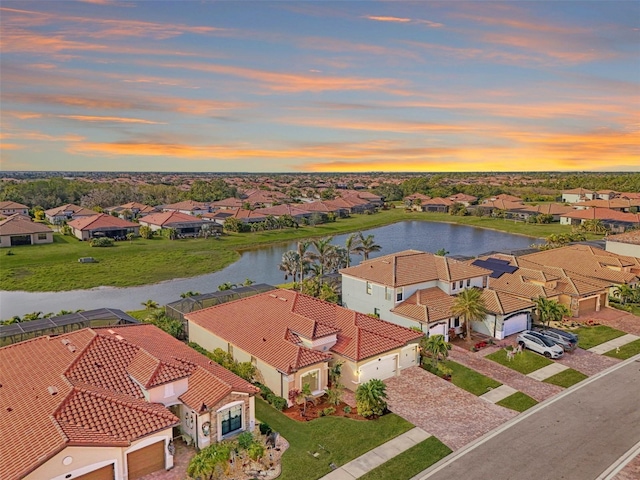 aerial view at dusk featuring a water view