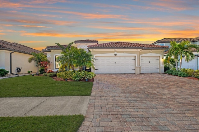 mediterranean / spanish home featuring a garage and a yard