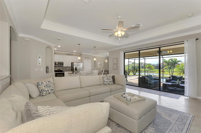 tiled living room with crown molding, a tray ceiling, and ceiling fan