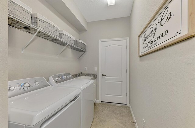 laundry room with light tile patterned flooring, washer and clothes dryer, and sink