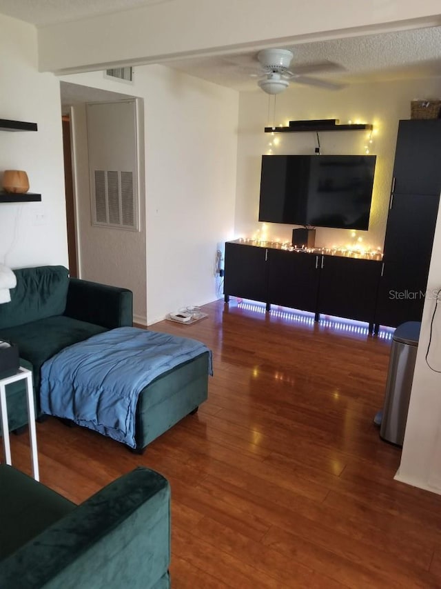 living room featuring ceiling fan, a textured ceiling, wood finished floors, and visible vents