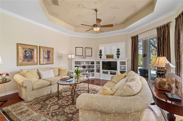 living room featuring a raised ceiling, crown molding, and wood-type flooring