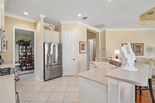 kitchen with stainless steel fridge, white gas range oven, a kitchen breakfast bar, a kitchen island with sink, and sink