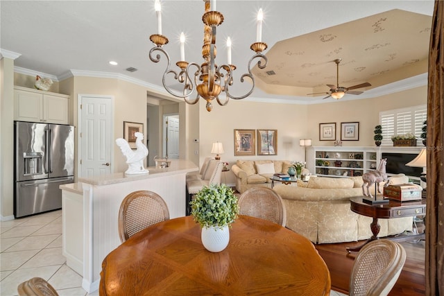 tiled dining room with ceiling fan with notable chandelier, a raised ceiling, and crown molding