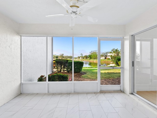 unfurnished sunroom with ceiling fan and a water view