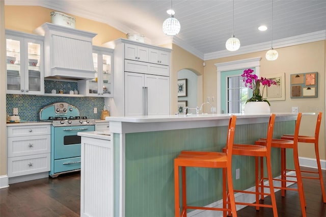 kitchen with a kitchen breakfast bar, dark hardwood / wood-style flooring, crown molding, pendant lighting, and range