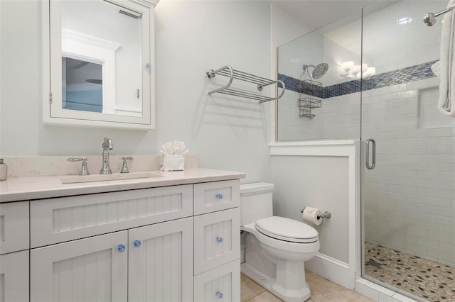 bathroom featuring tile patterned flooring, vanity, toilet, and a shower with shower door