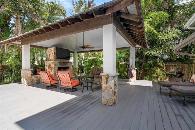 wooden deck featuring ceiling fan and an outdoor stone fireplace