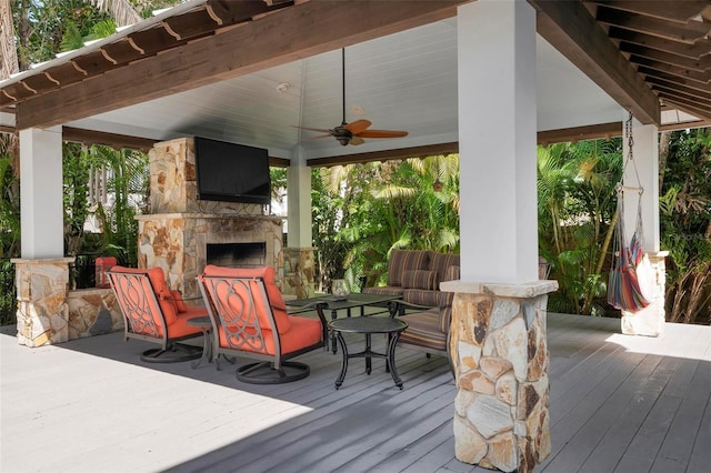 wooden deck featuring an outdoor stone fireplace and ceiling fan