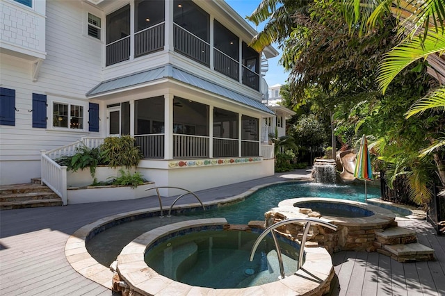 view of pool with an in ground hot tub, pool water feature, and a sunroom