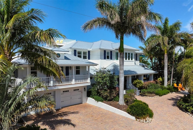 view of front of house with a balcony, decorative driveway, an attached garage, and metal roof