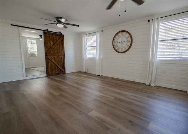 interior space featuring wood-type flooring, a barn door, cooling unit, and wood walls