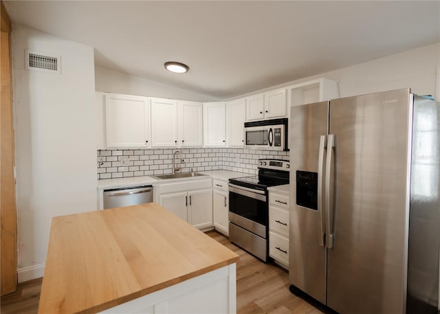 kitchen featuring a center island, sink, decorative backsplash, white cabinetry, and stainless steel appliances