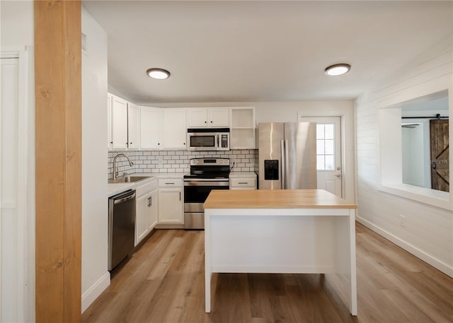 kitchen featuring sink, stainless steel appliances, tasteful backsplash, light hardwood / wood-style floors, and white cabinets