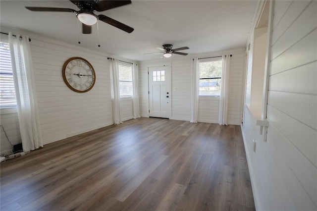 interior space featuring wooden walls, ceiling fan, and dark wood-type flooring