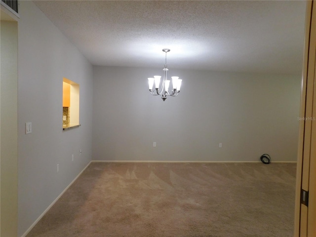 carpeted empty room with a textured ceiling and an inviting chandelier