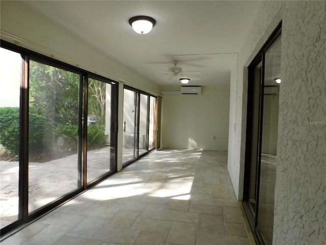 unfurnished sunroom featuring a wall unit AC and ceiling fan