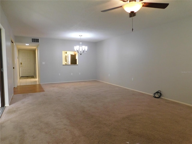 carpeted spare room with ceiling fan with notable chandelier