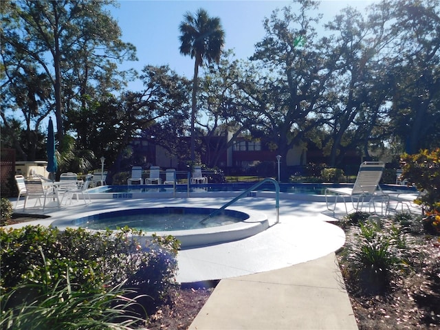 view of community with a patio and a pool with hot tub