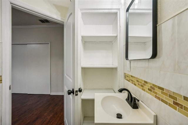 bathroom with hardwood / wood-style flooring, backsplash, crown molding, and sink