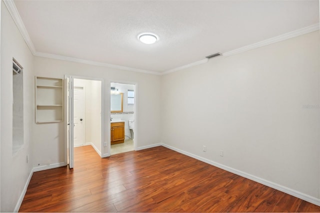 spare room with hardwood / wood-style floors, crown molding, and a textured ceiling