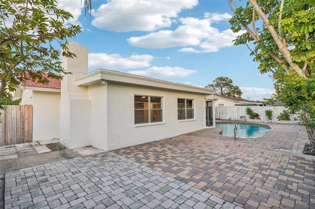 back of property featuring a fenced in pool and a patio