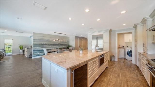 kitchen featuring wine cooler, hardwood / wood-style flooring, a large island, light stone counters, and washer / clothes dryer